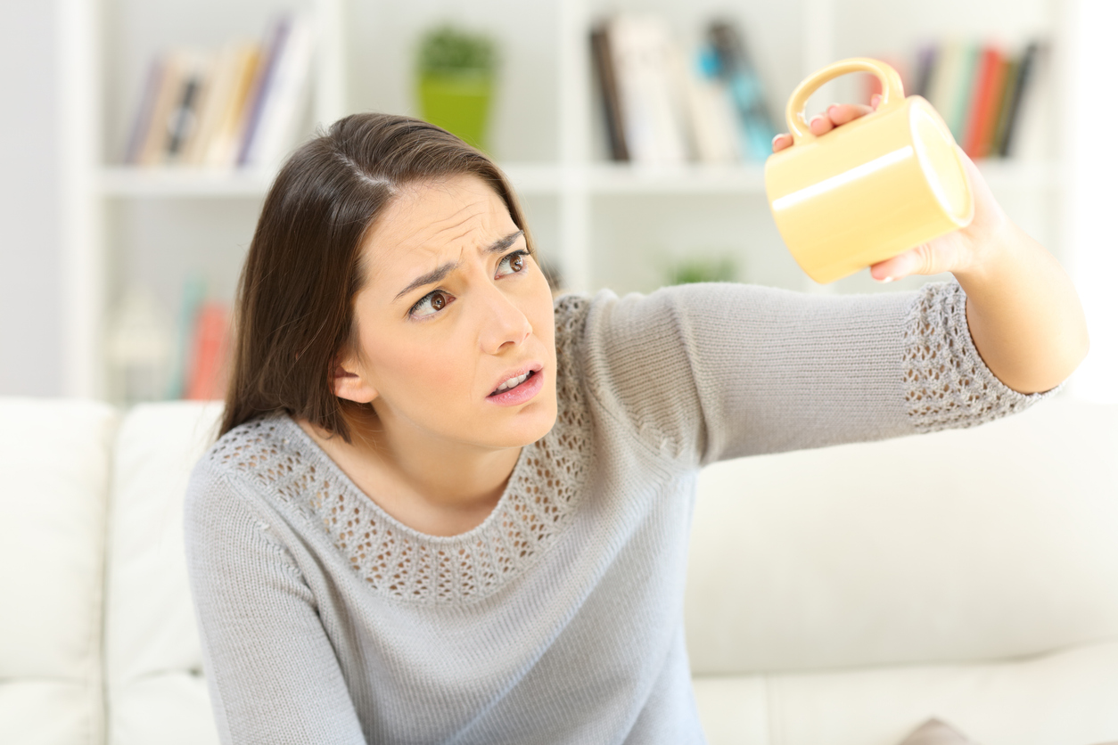 EIne Frau mit braunen Haare schaut verdutzt und traurig in ihre leere Kaffeetasse